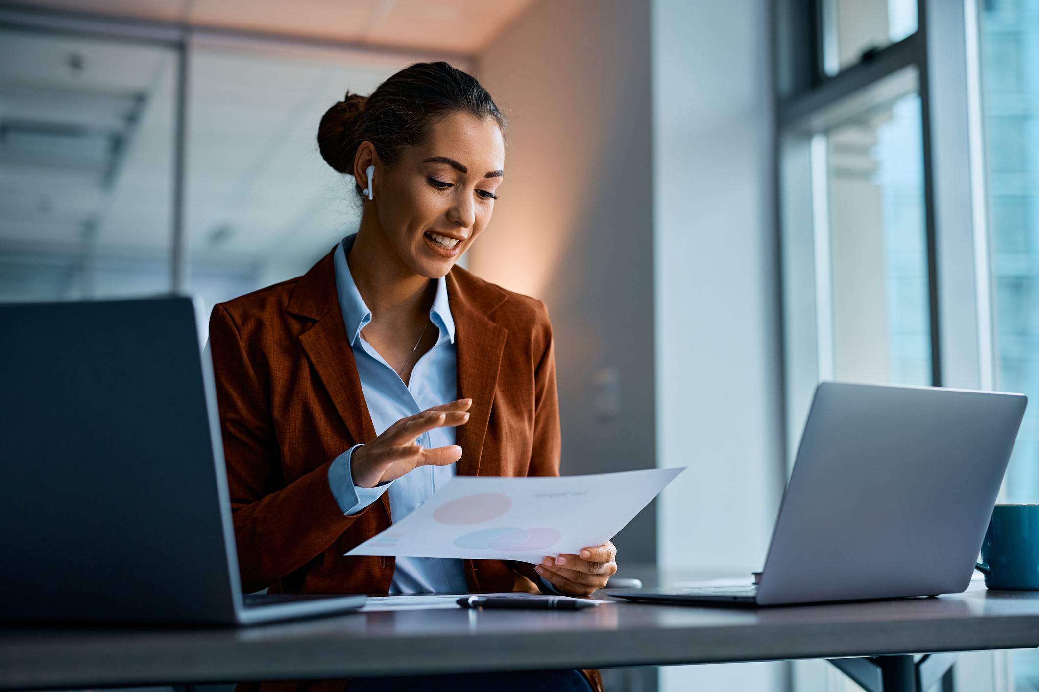 Young businesswoman analyzing documents while working on a computer in the office.